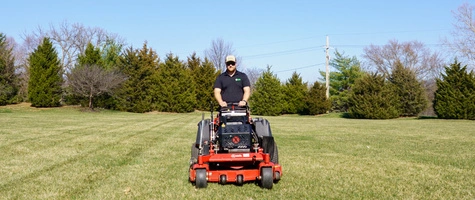Worker mowing large lawn in Olathe, KS.